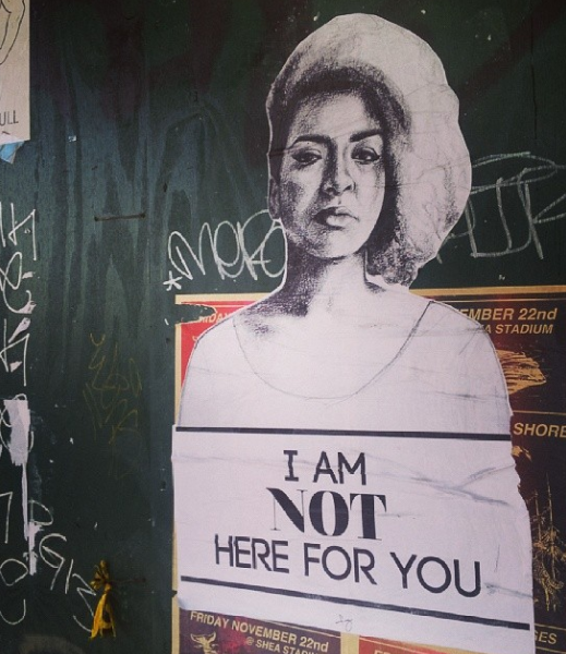 Wheatpaste on the side of a building has drawing of a female-presenting individual with the text: “I am NOT here for you.”
